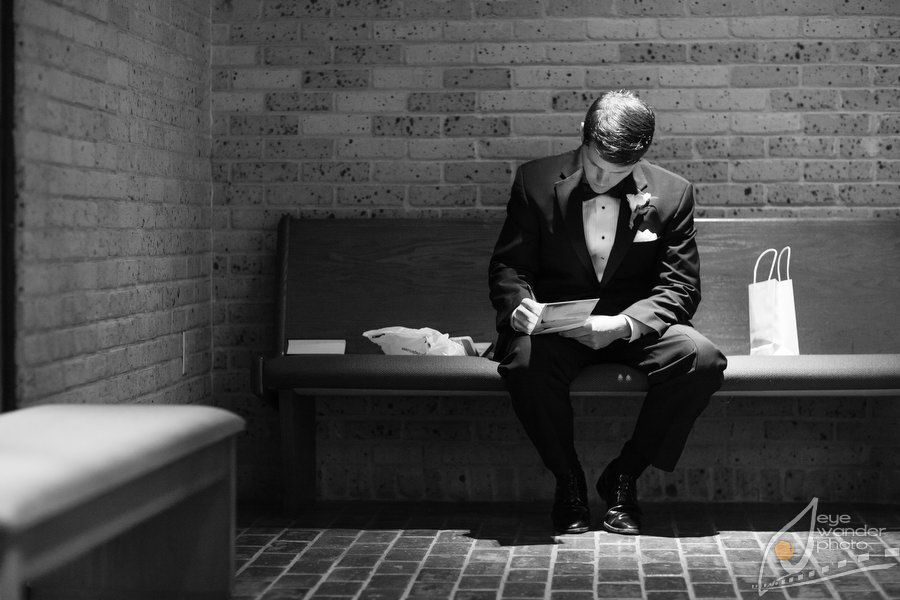 New orleans Wedding Ceremony Groom Sits on Church Pew Writing